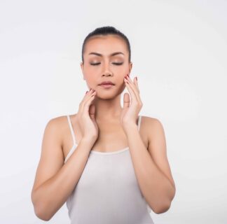 Beautiful young woman with clear fresh skin gently touching her face