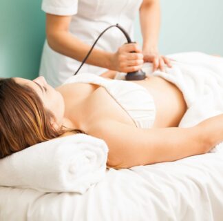 Female therapist performing body contouring treatment on client focusing on abdominal area